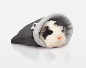 May include: A grey and white guinea pig sleeping in a grey fleece sleeping bag. The sleeping bag has a white fleece lining.