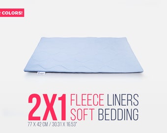 Puede incluir: Dos forros de forro polar azul claro para la cama de mascotas. Los forros miden 77 cm por 42 cm. El texto "2X1 FLEECE LINERS SOFT BEDDING" está impreso en rojo sobre un fondo blanco.