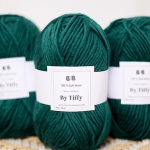 May include: Three balls of dark green 100% soft wool yarn, each with a white label that reads "100% Soft Wool", "Made in Bulgaria", "By Tiffy", "WWW.THETIFFYMOHAIR.COM", "100g / 100 m".
