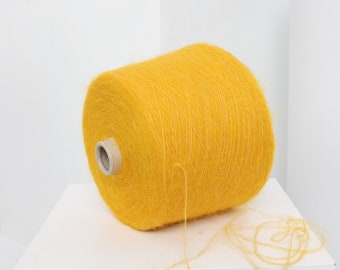 Pode incluir: Uma bobina de fio amarelo brilhante com uma ponta solta pendurada do lado. O fio é macio e felpudo, e é perfeito para tricotar ou fazer crochê.