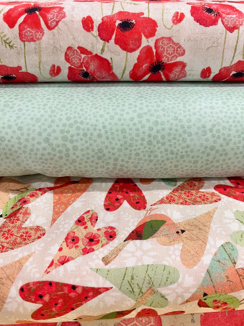 May include: Three fabric swatches with different patterns. The top swatch features a white background with red poppy flowers. The middle swatch is a solid green with a subtle speckled pattern. The bottom swatch has a white background with a repeating pattern of red hearts, birds, and leaves.