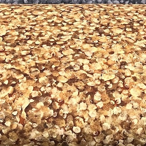 May include: A brown and beige fabric with a pattern of small, irregular circles. The fabric has a subtle texture and a slightly distressed look.