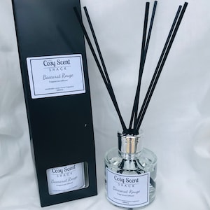 May include: A black box with a white label that reads "The Cosy Scent Shack Baccarat Rouge Fragranced Diffuser Handmade Luxury Home Fragrance 100ml e" and a clear glass bottle with a silver lid and black reeds. The bottle label reads "Cosy Scent Shack Baccarat Rouge Fragranced Diffuser Handmade Luxury Home Fragrance 100ml e".
