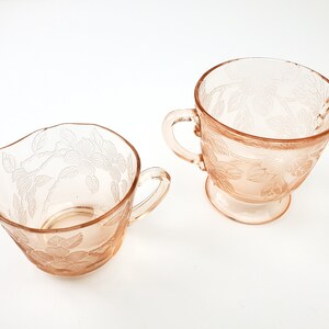 May include: A set of two vintage pink glass creamer and sugar bowls with a floral design.