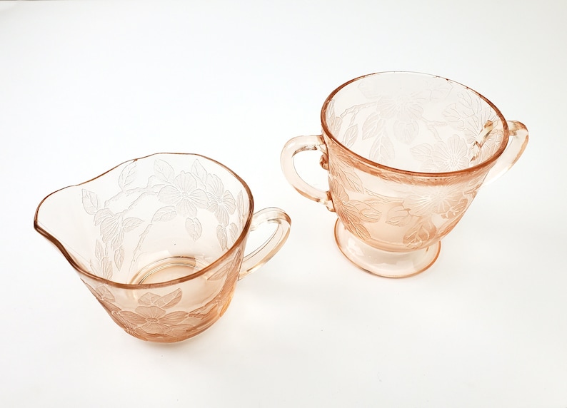 May include: A set of two vintage pink glass creamer and sugar bowls with a floral design.