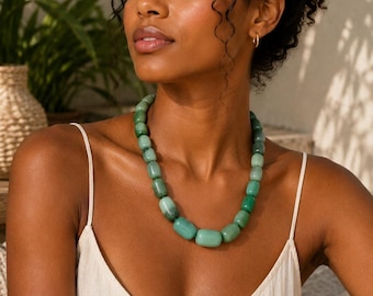 May include: A necklace featuring smooth, cylindrical beads in varying shades of light and dark green. The beads are strung together in a single strand, creating a uniform, rounded shape that rests around the neck. The necklace has a polished finish.