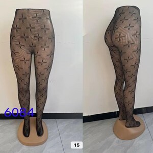 May include: Black fishnet tights with a repeating cross pattern. The tights are displayed on a mannequin leg. The number "6084" is printed on the lower left side of the image, and the number "15" is printed on the lower right side.
