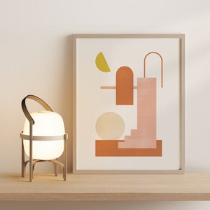 May include: A framed print with an abstract geometric design in shades of pink, orange, and yellow. The design features a pool with a diving board and a ladder, and a yellow sun.
