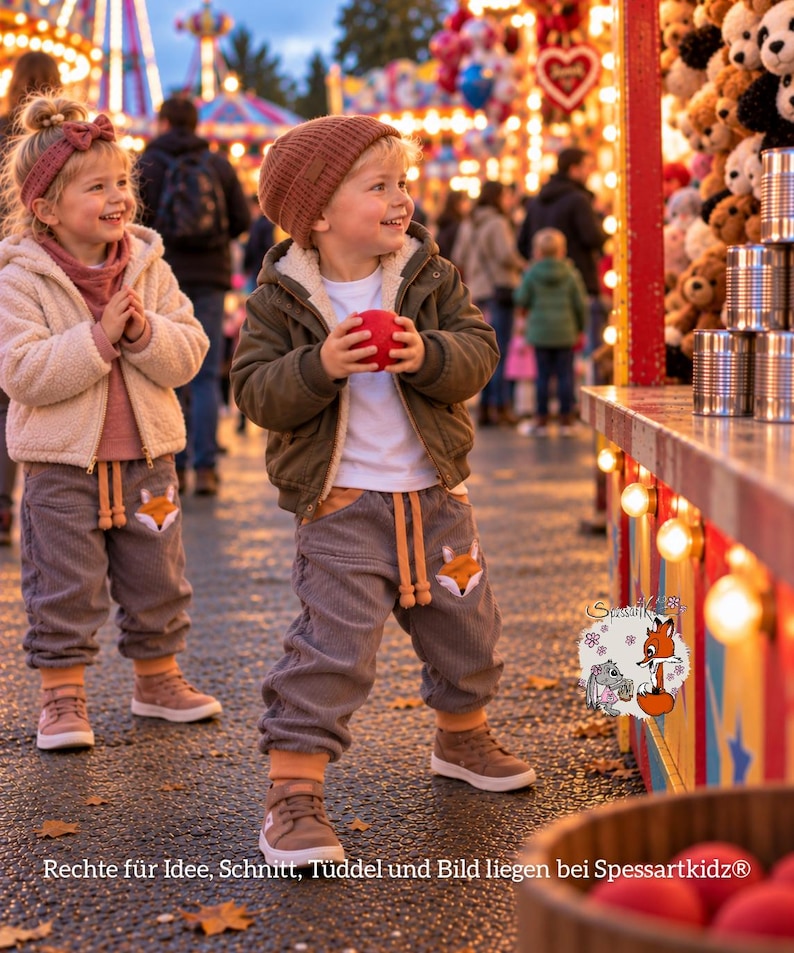 May include: Two children wearing grey corduroy joggers with fox face appliques, beige and olive jackets, and knit hats. The joggers feature drawstring waists and orange cuffs. A logo with a fox and rabbit illustration includes the text Spessartkidz.