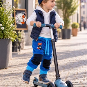 May include: A child wearing a navy blue beanie, a white hooded sweatshirt, a navy blue quilted vest, and blue corduroy pants with black knee patches and a fox graphic. The child is standing on a blue and black three-wheeled kick scooter.