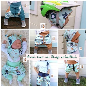 May include: A collage of images featuring baby and toddler clothing with a raccoon print. The clothing includes pants, a hat, and a bib. The text "Auch hier im Shop erh&auml;ltlich" is visible in the image.