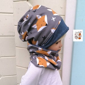 Könnte beinhalten: Grau-oranges Mützen- und Halssocken-Set mit Fuchs-Druck. Die Mütze hat ein blaues Fleece-Futter. Der Halssocken ist im Cowl-Stil.