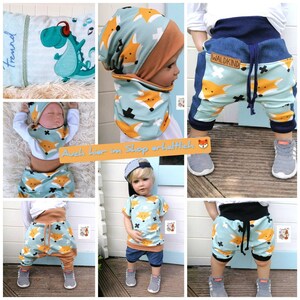 May include: A set of baby clothes featuring a fox print in blue, orange, and white. The set includes a beanie, a bib, a short-sleeved shirt, and a pair of shorts. The shorts have a denim panel on the side and a drawstring.