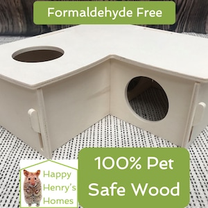 Könnte beinhalten: Weißes, eckiges Hamsterhaus aus Holz mit zwei runden Öffnungen. Das Haus ist mit "Happy Henry's Homes" und "100% Haustiersicheres Holz" beschriftet. Das Etikett weist auch darauf hin, dass es "Formaldehydfrei" ist.