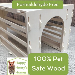 Könnte beinhalten: Weißes Holzspielhaus für Hamster mit Tunnel und Regalen. Das Spielhaus ist aus 100% tiersicherem Holz gefertigt und frei von Formaldehyd. Der Text "Happy Henry's Homes" befindet sich in der linken unteren Ecke des Bildes.