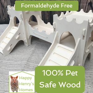 May include: A white wooden castle-style pet habitat featuring two slides, arched doorways, and a connecting bridge. The product is labelled "Formaldehyde Free" and "100% Pet Safe Wood". The Happy Henry's Homes logo is visible.