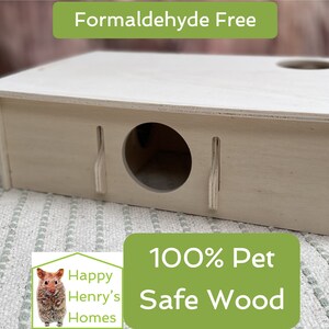 May include: A light wood hamster house with two entrances and a flat roof. The house is labelled "100% Pet Safe Wood" and "Formaldehyde Free".