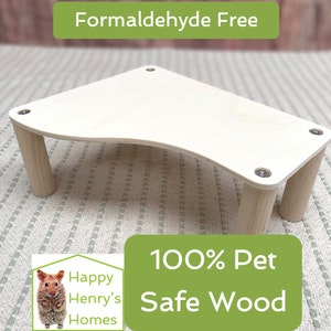 Könnte beinhalten: Eine helle Holzplattform mit abgerundeten Kanten und vier Beinen. Die Plattform ist aus 100% tiersicherem Holz gefertigt und frei von Formaldehyd. Der Text "Happy Henry's Homes" und "100% Pet Safe Wood" ist auf dem Bild zu sehen.