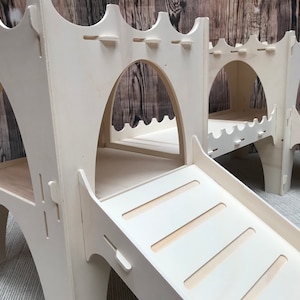 May include: White wooden play structure with two arched openings and a slide. The slide has five steps leading up to the top.