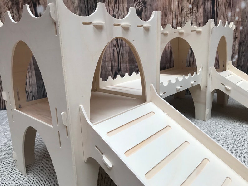 May include: White wooden play structure with two arched openings and a slide. The slide has five steps leading up to the top.