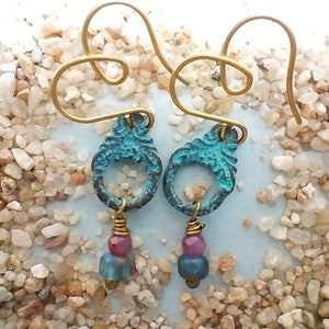 Puede incluir: Pendientes de metal azul turquesa con un encanto colgante de tres cuentas en tonos azules, rosa y marrón.