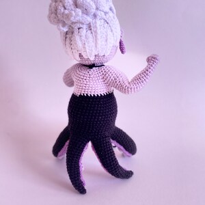 May include: A crocheted octopus doll with a white hair bun, purple bodice, and black tentacles.