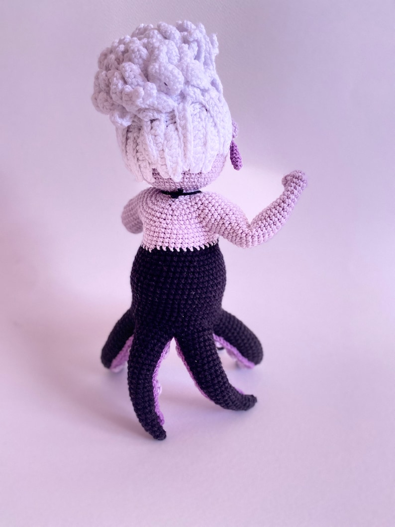 May include: A crocheted octopus doll with a white hair bun, purple bodice, and black tentacles.