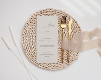 May include: A simple wedding menu card with a beige background and black text. The menu includes salad, main course, and dessert options. The card is placed on a woven placemat with gold cutlery and a beige ribbon.