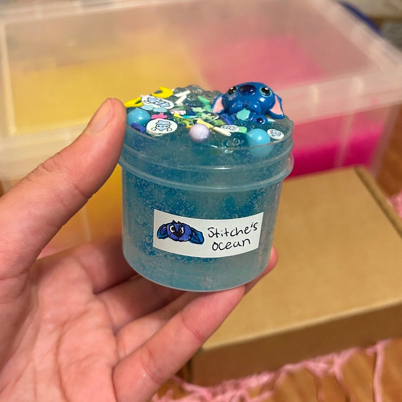 May include: Blue slime in a clear jar with a blue Stitch character on top. The jar has a white label that says "Stitch's Ocean".