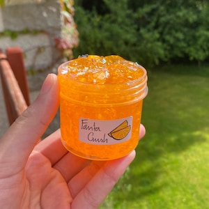 May include: Orange slime in a clear jar with a label that says "Fanta Gush" and a picture of orange slices.