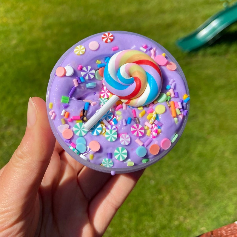 May include: Purple slime with a rainbow lollipop, sprinkles, and colorful candy pieces.