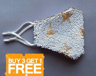 May include: White face mask with gold star sequins. The mask has adjustable elastic ear loops. The text "BUY 3 GET 1 FREE" is in the lower left corner of the image.