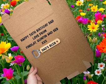 May include: A brown cardboard box with the text "HAPPY 50TH BIRTHDAY DAD LOVE FROM FINDLAY, QUINTIN AND SEB XXX" and a wooden bottle opener that reads "DAD'S BEER". The box is set against a backdrop of colorful flowers.