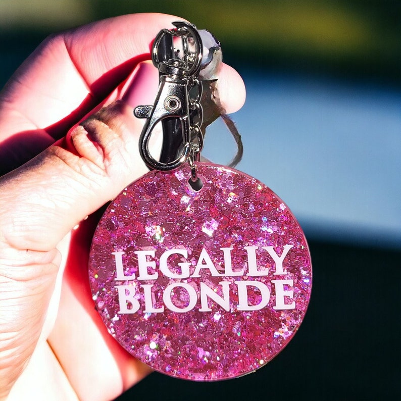 May include: Pink glitter keychain with the text "LEGALLY BLONDE" in white lettering.