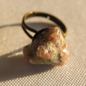 May include: A ring with a raw, pink and white crystal stone set in a brass band.