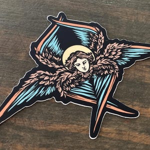 Może przedstawiać: Naklejka przedstawiająca szczegółową ilustrację anioła z rozpostartymi skrzydłami. Anioł ma aureolę i jest przedstawiony z pogodnym wyrazem twarzy. Skrzydła są niebieskie i czarne z brzoskwiniowymi akcentami. Naklejka ma białą obwódkę.