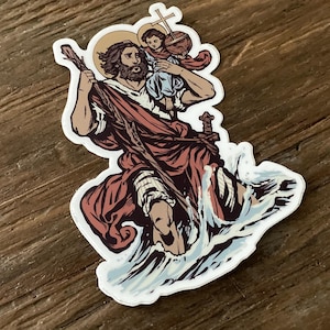 Puede incluir: Una pegatina con una ilustración colorida de un hombre que sostiene a un niño, caminando sobre el agua. El hombre lleva una túnica roja y sostiene un bastón. El niño lleva una túnica azul y sostiene una cruz. El fondo es un patrón de olas azules y blancas.