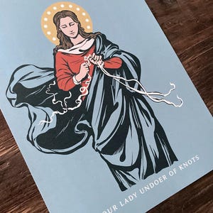 May include: A blue and red illustration of Our Lady Undoer of Knots, a Catholic icon depicting the Virgin Mary untying a knotted rope. The image is set against a light blue background.