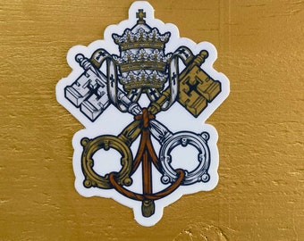May include: A white sticker with a gold and white papal keys and tiara design. The keys are crossed and the tiara is above them. The design is on a gold background.
