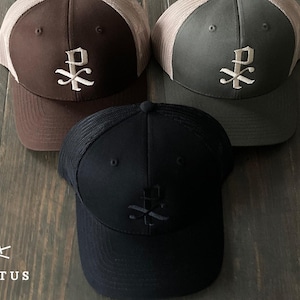 Könnte beinhalten: Drei Baseballkappen mit Mesh-Rücken. Eine ist braun mit beigem Mesh, eine andere ist grau mit beigem Mesh und die dritte ist schwarz mit schwarzem Mesh. Jede Kappe hat ein weißes gesticktes Design auf der Vorderseite.
