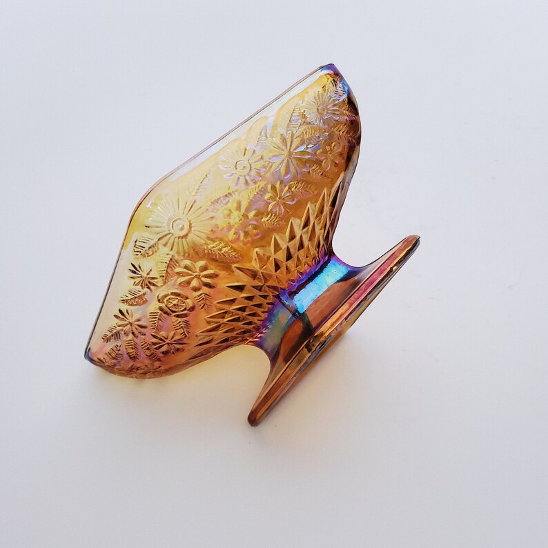 May include: A vintage iridescent amber glass bowl with a floral pattern and a pedestal base.