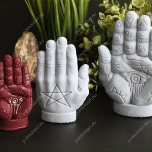 May include: Three hand-shaped sculptures with esoteric symbols. One is burgundy, the others are white. The burgundy hand features an eye symbol. The white hands have a pentagram and an eye symbol. The sculptures are likely used for decorative or spiritual purposes.