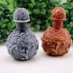 May include: Two decorative potion bottles. One is a dark gray color, and the other is a reddish-brown color. Both bottles have ornate, swirling designs and a round shape. The word "Potion" is visible on the gray bottle.