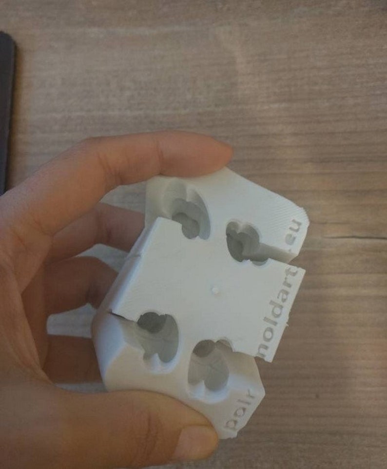 Puede incluir: Un molde blanco de tres partes con recortes en forma de coraz&oacute;n. El molde est&aacute; hecho de un material pl&aacute;stico duro y tiene el texto "moldart.eu" y "polr" impreso. El molde est&aacute; dise&ntilde;ado para crear objetos con forma de coraz&oacute;n.