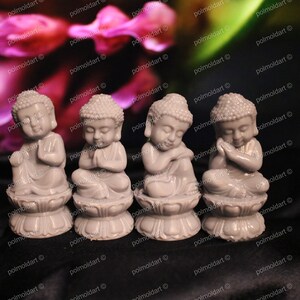 May include: Four small, gray Buddha statues in various meditative poses. Each figure sits atop a lotus flower base. The background features a blurred floral pattern with shades of pink and green.
