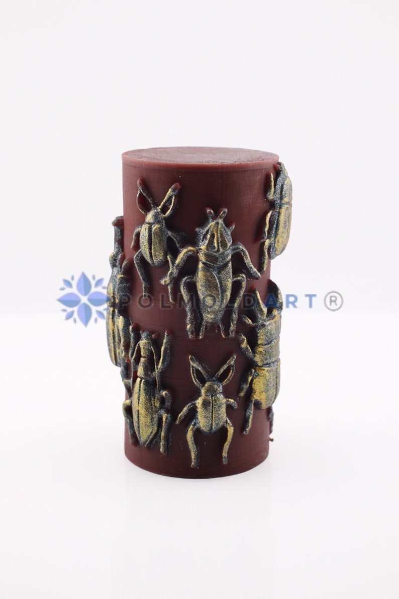 Pu&ograve; includere: Una candela cilindrica bordeaux decorata con disegni di scarabei dorati in rilievo. La candela ha una superficie liscia ed &egrave; adornata da varie forme di insetti, creando un pezzo decorativo unico.
