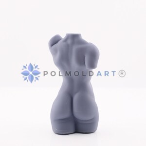 May include: A grey sculpture of a human torso, viewed from the back. The form is smooth and stylized, with defined musculature. The sculpture is on a white background. The text "POLMOLDART&reg;" is visible.
