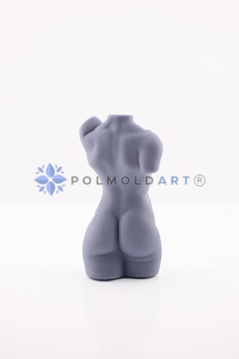 May include: A grey sculpture of a human torso, viewed from the back. The form is smooth and stylized, with defined musculature. The sculpture is on a white background. The text "POLMOLDART&reg;" is visible.