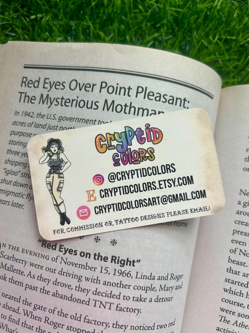 May include: A rectangular business card with rounded corners featuring the colorful text Cryptid Colors, an illustration of a person in a dark top and light pants, and contact information including an Instagram handle, Etsy URL, and email address.