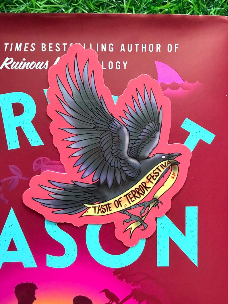 May include: A die-cut sticker featuring a black crow with spread wings, set against a vibrant pink background. The crow holds a yellow banner in its talons with the black text TASTE OF TERROR FESTIVAL printed clearly across the ribbon surface.